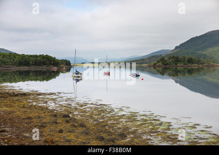 Barche ormeggiate su una calma piatta Loch Leven. Foto Stock