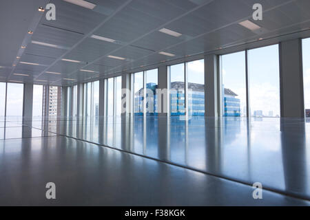 Vuoto ufficio moderno camera con grandi finestre e di riflessioni sul pavimento Foto Stock