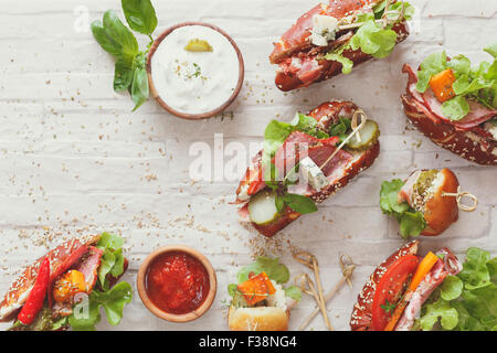 Panini. Un assortimento di mini panini con varietà di riempimento su sfondo rustico con uno spazio vuoto Foto Stock