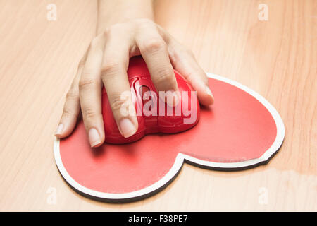 Mano femminile con il mouse del computer sul tavolo.Il giorno di san valentino Foto Stock