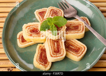 Bolo de rolo (swiss roll, roll cake) dessert brasiliano sulla piastra verde sul bambù. Messa a fuoco selettiva Foto Stock