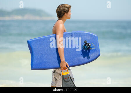 RIO DE JANEIRO, Brasile - 20 febbraio 2014: giovane brasiliano surfer passeggiate con scheda corpo lungo la riva della spiaggia di Ipanema. Foto Stock