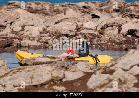 Madre e figlia giovane vela su un kayak in mare tra gli scogli. Foto Stock