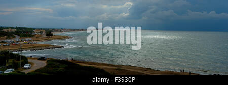 Avvicinando storm su una spiaggia del Gargano. Il sole filtra attraverso un foro nelle nuvole e tempestoso Foto Stock