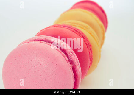 Primo piano di alcuni appetitosi macarons di colori pastello e sapori diversi su sfondo bianco Foto Stock