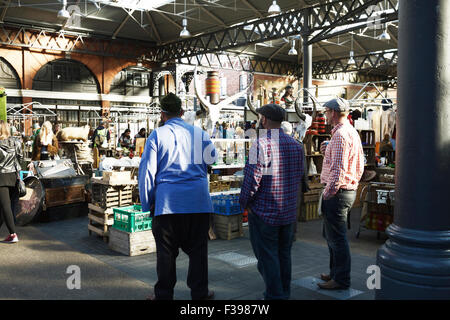 Il mercato di antiquariato al giorno, a Spitalfields Market di Londra, Inghilterra, Regno Unito. Gli operatori di mercato a guardare i clienti. Foto Stock