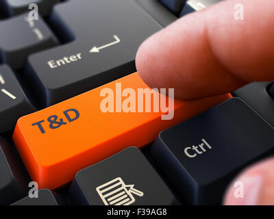 Un dito preme il pulsante arancione la formazione e lo sviluppo - nero sulla tastiera del computer. Primo piano. Messa a fuoco selettiva. Foto Stock