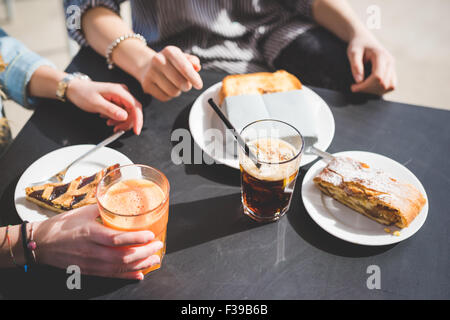 Due donne amici avente un happy hour in un bar - focus sul tavolo con torta, toast e succo di frutta - aperitivo, snack, concetto rilassante Foto Stock