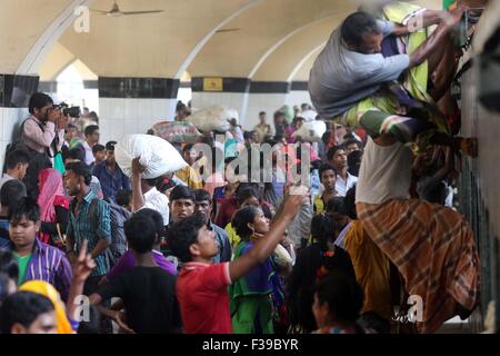 Persone, compresi bambini, scendere dal tetto di un treno in entrata a kamalapur stazione ferroviaria a Dhaka il 1 ottobre 2015.in quanto non vi è stato alcun spazio interno, hanno viaggiato sul tetto, rischiando la vita ed il ramo di ritorno in città dopo le vacanze Eid. Foto Stock