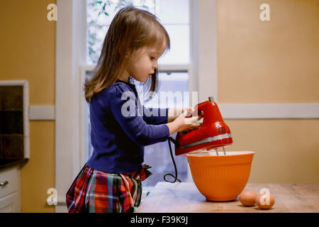 Ragazza con un mixer elettrico in cucina Foto Stock