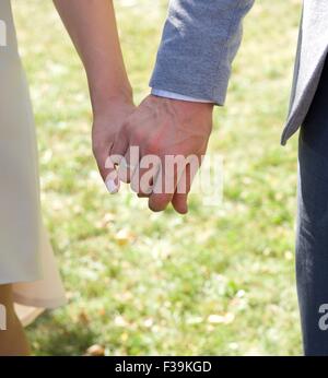 Close-up di una sposa e lo sposo tenendo le mani al loro matrimonio Foto Stock