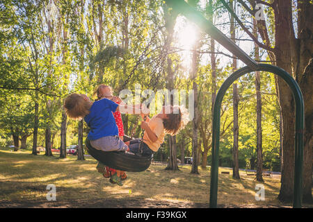 Tre bambini che giocano su uno swing Foto Stock