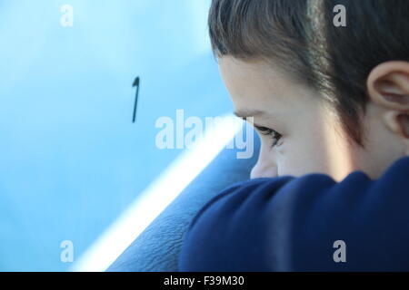 Close-up verticale di un ragazzo che guarda fuori da una finestra su un viaggio in treno Foto Stock