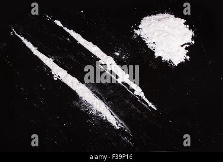 La cocaina in polvere in linee su uno sfondo nero Foto Stock