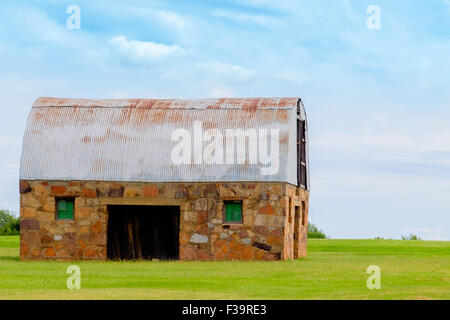 Un fienile in pietra con un arrugginito tin roof in Oklahoma, Stati Uniti d'America campagna. Foto Stock