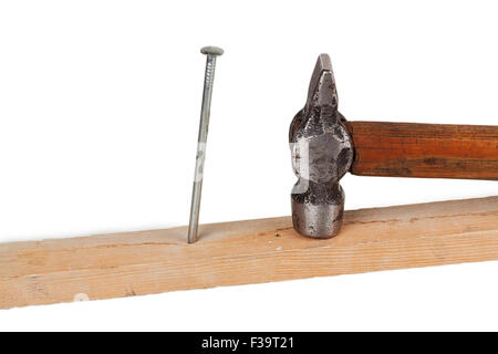 Il martello e il chiodo in una tavola di legno isolato su sfondo bianco Foto Stock