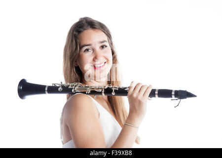 Bruna giovane donna detiene il clarinetto in studio sulla sua spalla e sorrisi contro uno sfondo bianco Foto Stock