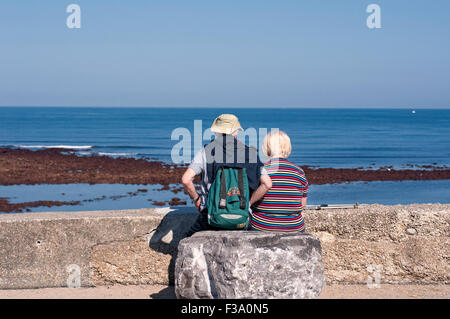 Coppia senior rilassante in una giornata di sole guardando il mare. Foto Stock