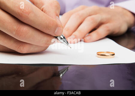 Primo piano della mano maschio firma carte di divorzio Foto Stock