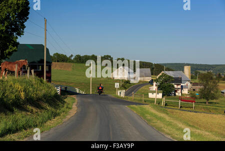 Lancaster County, Pennsylvania Amish cavallo e buggy quadrato sulla strada di campagna passato edifici agricoli Foto Stock