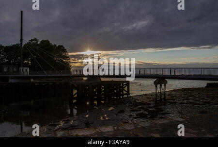 Silhouette di un tramonto oltre il ponte sull'acqua Foto Stock