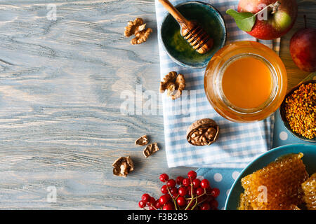 Prodotti apistici ancora in vita: un vasetto di miele, favi. teabowls di bee di polline e di miele con bilanciere, noci Mele fresche e una b Foto Stock