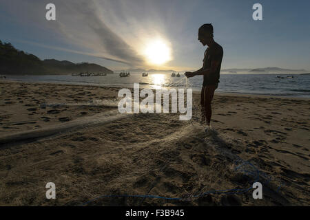 Jember, Indonesia-August 02, 2015:locale e tradizionale fisherman riparare la sua rete da pesca in spiaggia Papuma, Jember. Foto Stock