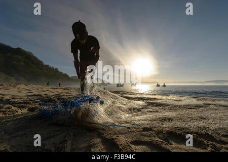 Jember, Indonesia-August 02, 2015:locale e tradizionale fisherman riparare la sua rete da pesca in spiaggia Papuma, Jember. Foto Stock