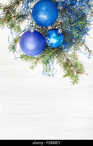 Auguri di Natale - Scheda di confine da tre blu e viola Xmas baubles e ramo di albero su carta bianca sullo sfondo Foto Stock