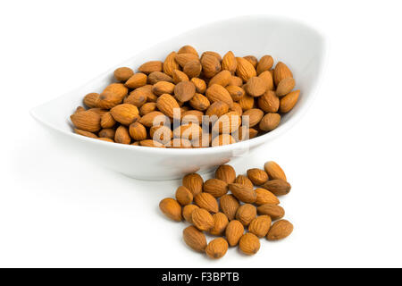 Pila di cracking e di mandorle sgusciate kernels nella ciotola bianco su sfondo bianco Foto Stock