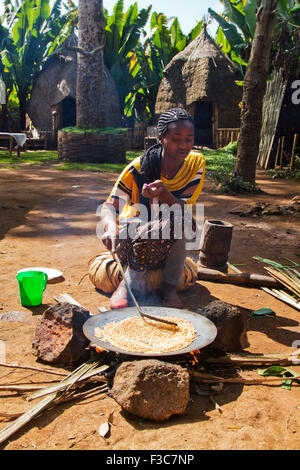 Donna Dorse arrosti i chicchi di caffè. Fotografato nella valle dell'Omo, Etiopia Foto Stock