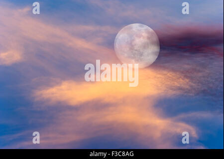 Luna nuvole del cielo è una vibrante surreale scenic di una luna piena in aumento tra i colorati cloudscape. Foto Stock