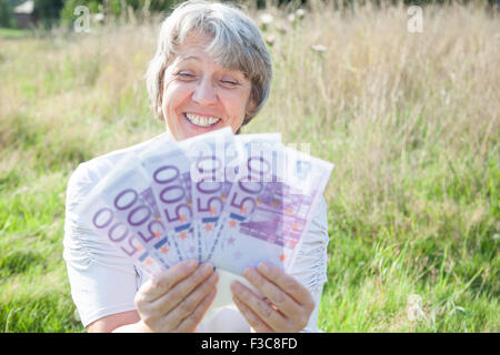 La vecchiaia donna tenendo un sacco di soldi Foto Stock