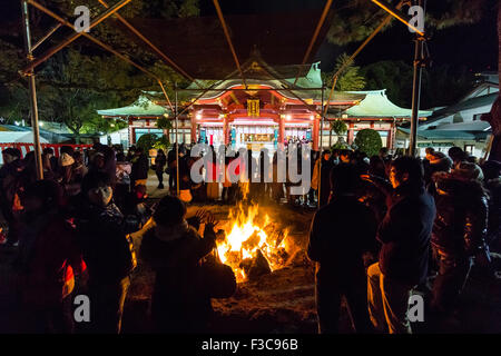 Anno nuovo, Giappone. Sacrario scintoista, Nishinomiya. La folla si riuniscono intorno al falò dove il precedente anno di buona fortuna charms, Omamori, sono saltati in. Notte. Foto Stock