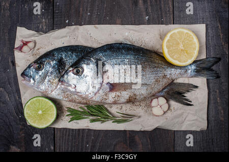 Pesce crudo e spezie sul tavolo di legno Foto Stock