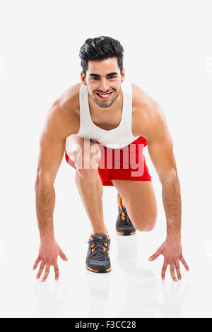 Athletic uomo pronto a correre, isolate su uno sfondo grigio Foto Stock