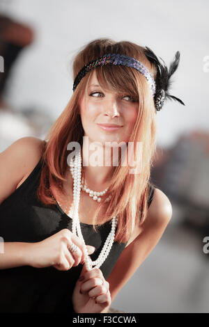 Enca ragazza ritratto. Stile retrò vintage moda donna dal fragore 1920s in archetto con filo di perle, all'aperto. Città bac Foto Stock