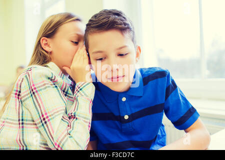 Sorridente schoolgirl whispering a classmate orecchio Foto Stock