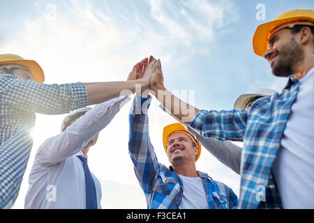 Close up dei costruttori in hardhats rendendo alta cinque Foto Stock