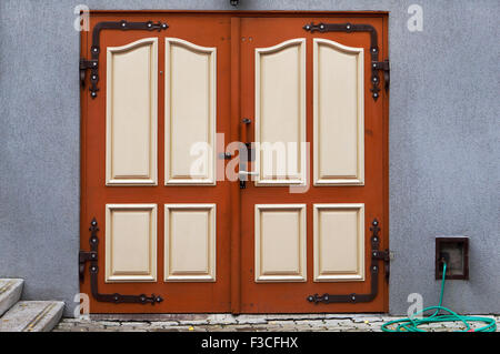 Il rosso corazzato cancelli in acciaio porta è camuffata sotto il legno. La produzione di massa Foto Stock