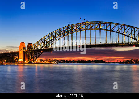 Vista laterale del Ponte del Porto di Sydney a sunrise con scarlett sun luce ed illuminazione di arco ancora Foto Stock