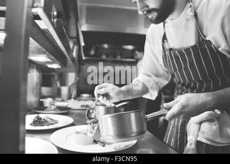 Lo chef prepara piatti di cibo Foto Stock