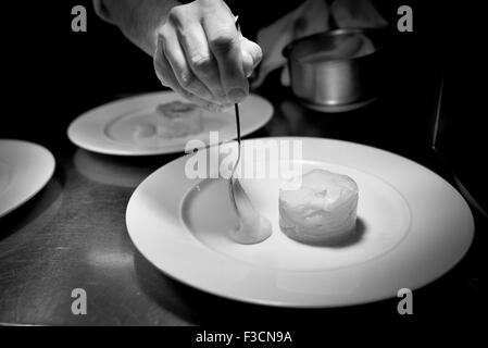 Lo Chef disponendo il cibo sulla piastra per la presentazione ottimale Foto Stock