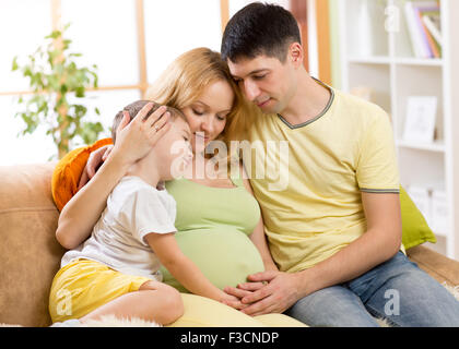 La famiglia felice in previsione della nascita del nuovo bambino. La donna incinta e il marito sul divano di casa Foto Stock