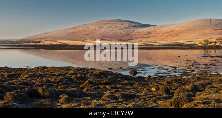 Ancora una mattina intorno ad Alba a Finavarra, Burren, County Clare, Irlanda, con le montagne calcaree si riflette nel mare Foto Stock