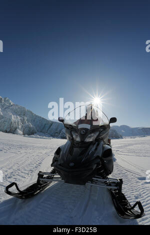 Elemento di spedizione guida con ski doo su ghiaccio dal mare ghiacciato con ghiacciaio e sun in background, Von Postbreen, Spitsbergen ( Foto Stock