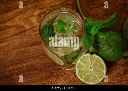 Cocktail Mojito con lime fresco sulla tavola di legno Foto Stock