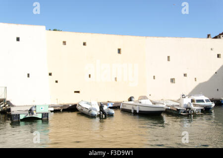 Fontage di un edificio beige con cielo blu e molte barche Foto Stock