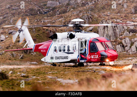 Il azionato Bristow Salvataggio in elicottero atterra su un terreno accidentato nella valle Ogwen, pronto per il salvataggio di un walker Foto Stock