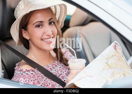 Donna sorridente con mappa in auto Foto Stock